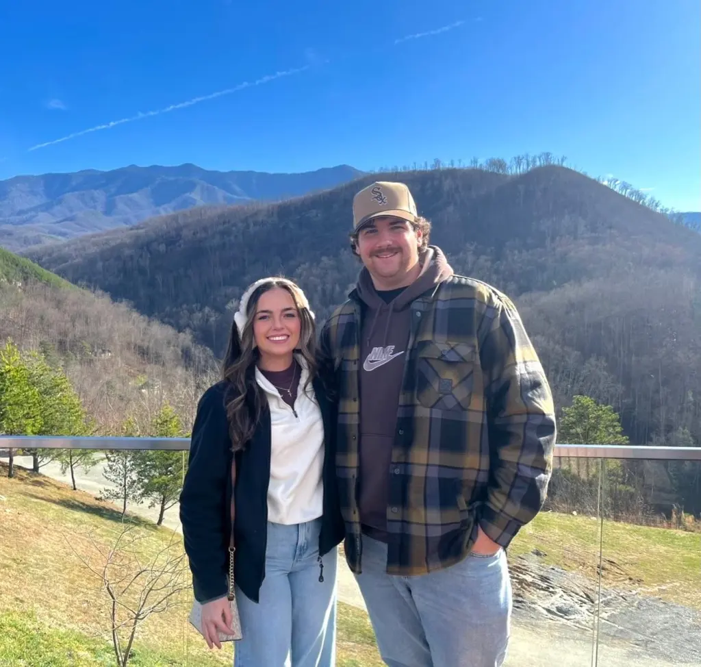 Leah Fonte and Shane Hirstius pose for a photo together in front of a mountainous landscape.