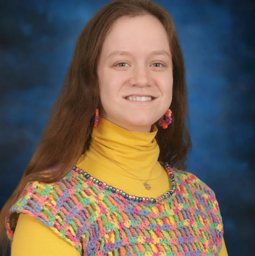 Mia Kurzer, a special education teacher, smiling in front of a blue background.