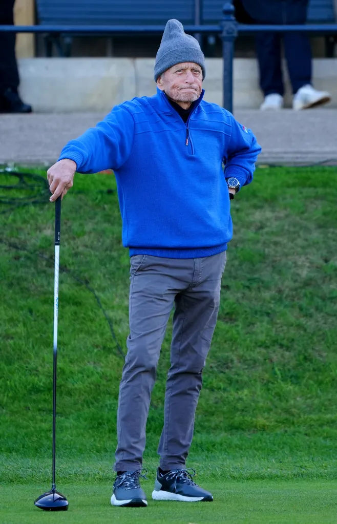 Michael Douglas leaning on a golf club on the 1st tee at the Alfred Dunhill Links Championship.