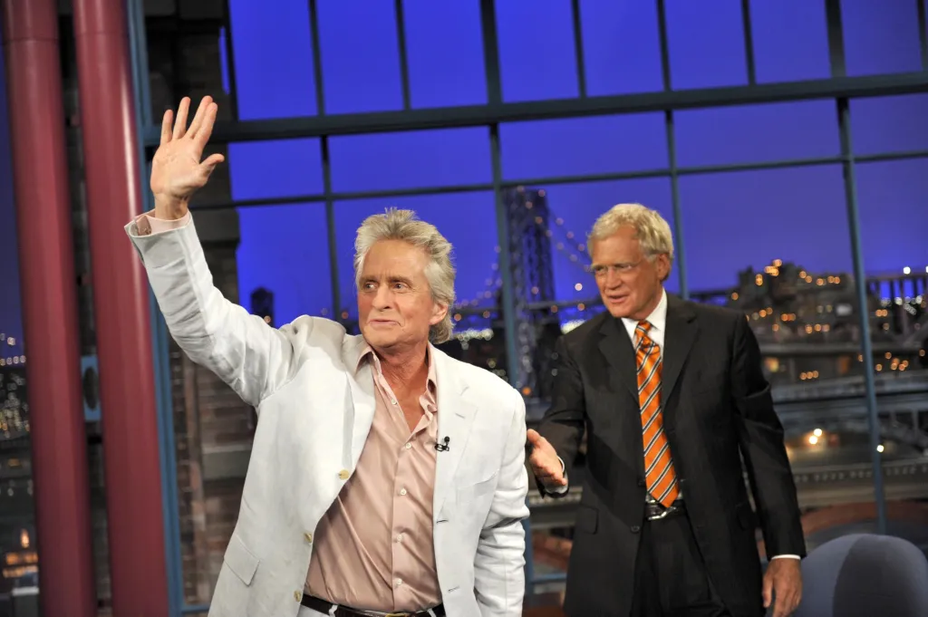 Michael Douglas waving to the audience alongside David Letterman.