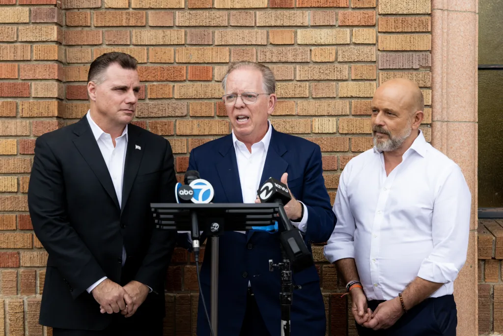 California attorney general candidate Michael Gates, California state controller candidate Herb Morgan, and Republican gubernatorial candidate Steve Hilton at a news conference in front of a brick wall.