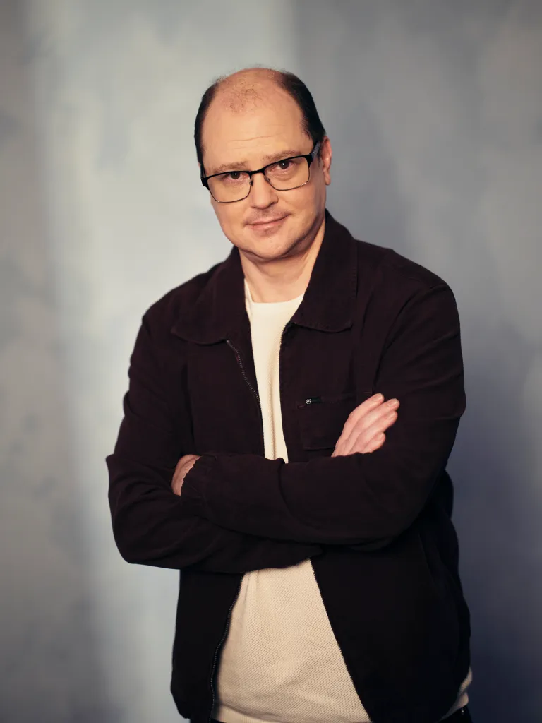 Mike Flanagan poses with his arms crossed in a portrait studio.