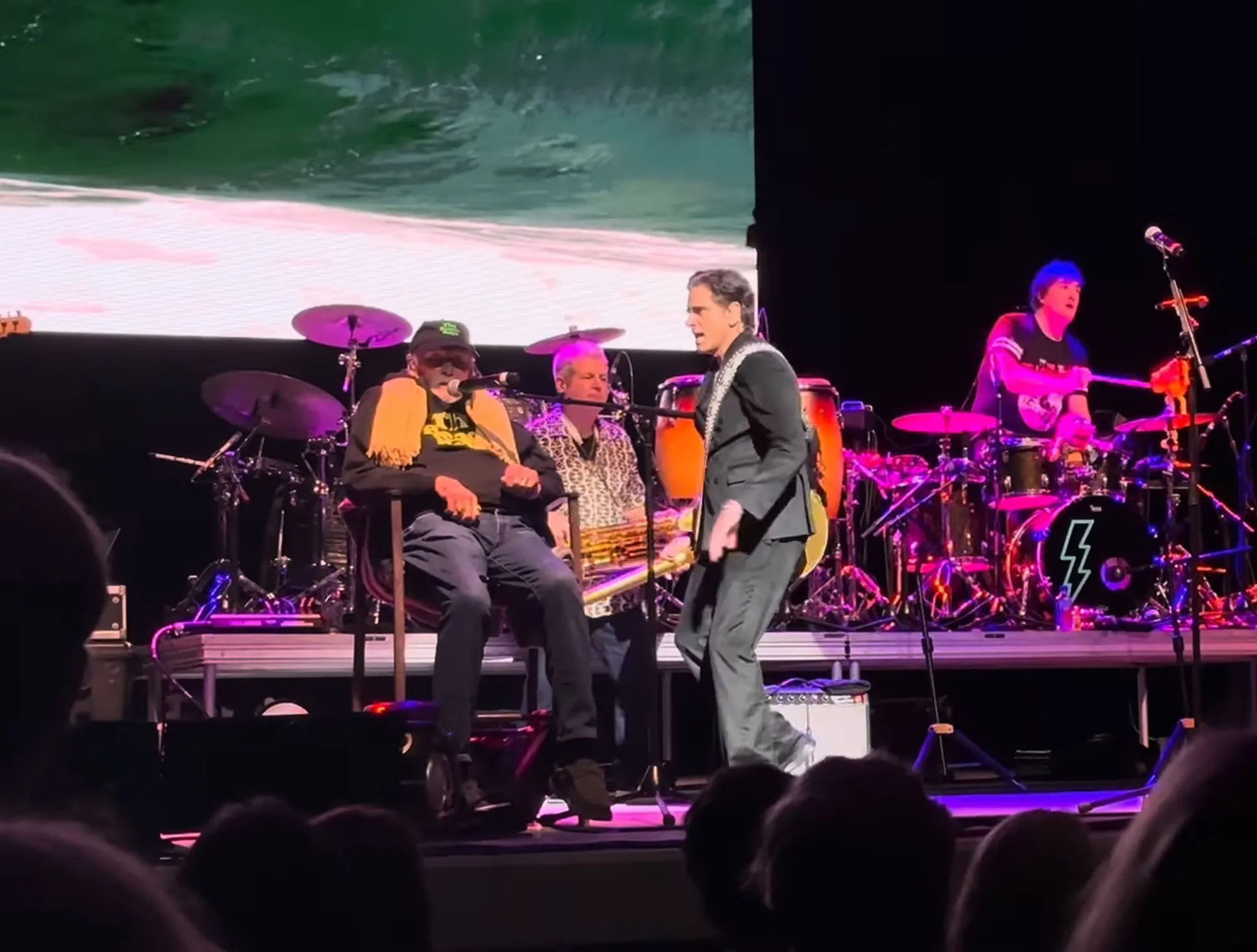Mike Love performs on stage with his band.