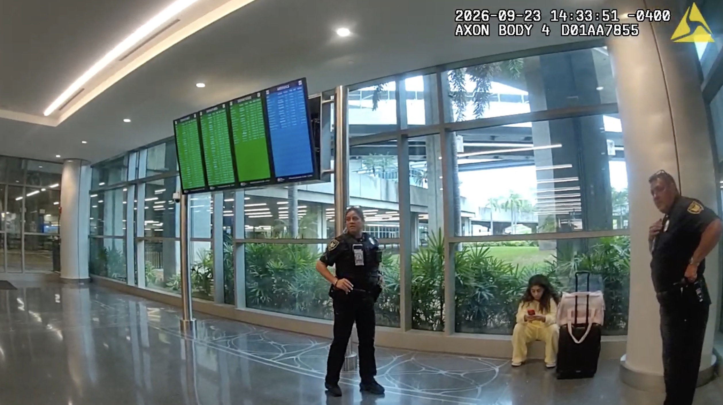 Bodycam footage shows Milania Giudice sitting next to a suitcase while police officers stand nearby in an airport.