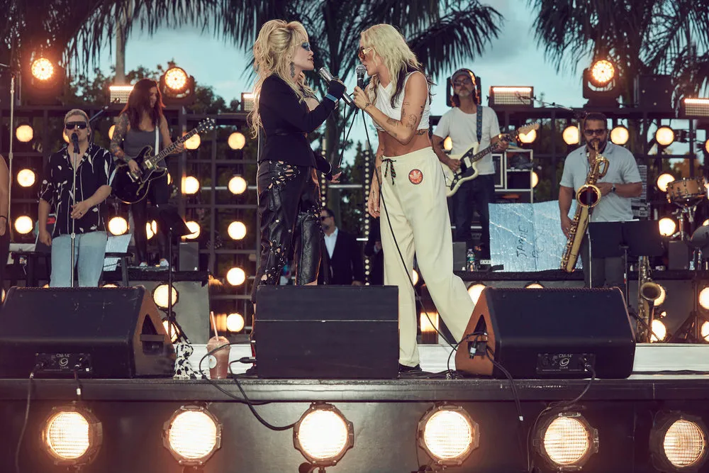 Dolly Parton and Miley Cyrus rehearse on stage with their band.