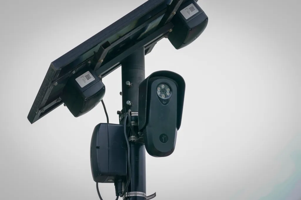 A Flock Safety camera mounted on a pole with a solar panel.