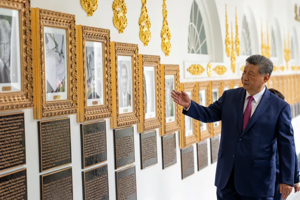 Chinese President Xi Jinping looks at framed photographs on a wall.
