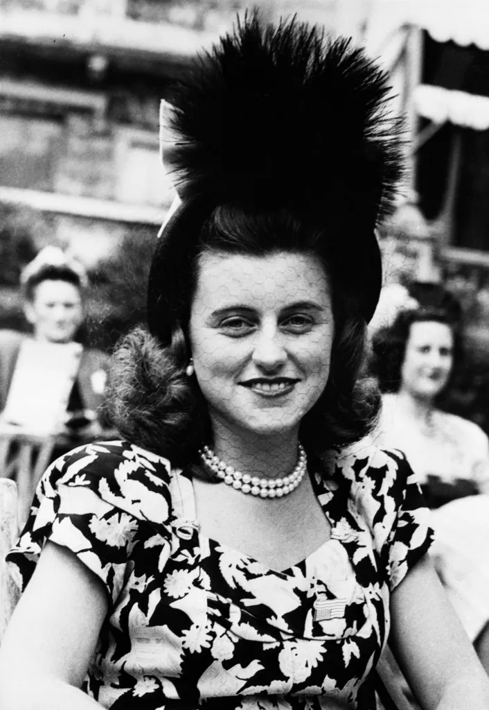 Miss Kathleen Kennedy wearing a large feathered hat and a floral dress.