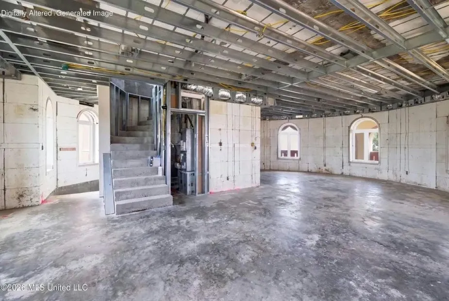 Unfinished interior of the Taj Mahal-inspired residence in Ocean Springs, showing concrete floors, framed walls, arched windows, and an exposed metal ceiling structure.