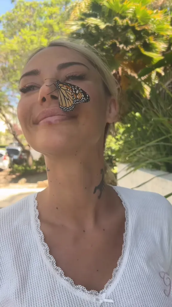 Sahara Ray with a monarch butterfly on her nose.