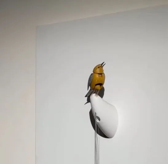 Molly, the animated bird sculpture perched on a white wall mount.