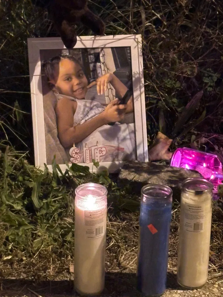 A framed photograph of Maya Thomas surrounded by candles and brush.