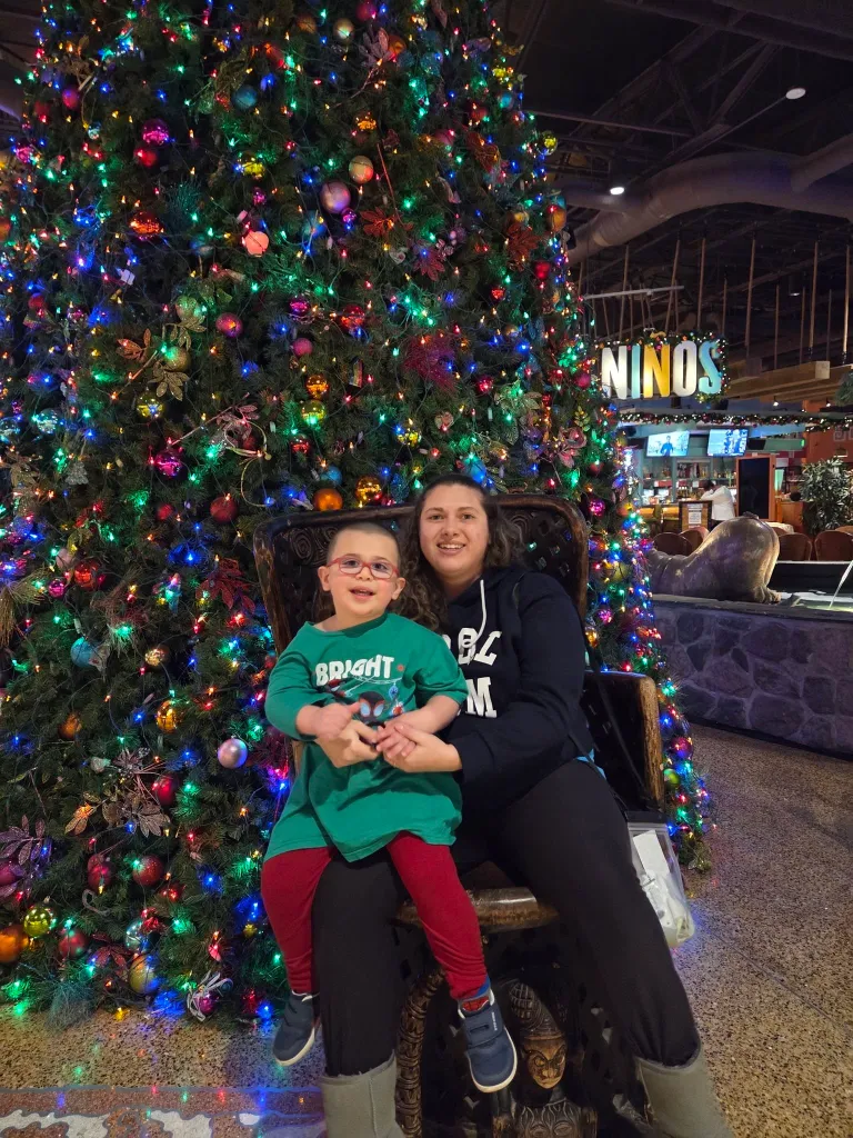 Metallica Rose Harrison and her three-year-old son sitting in front of a large Christmas tree.