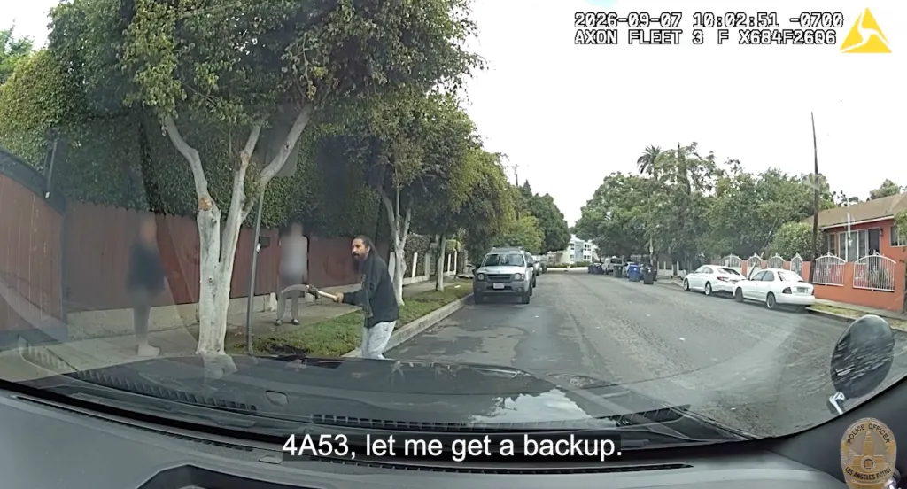 Bodycam footage shows a man holding a pole saw on a suburban street.
