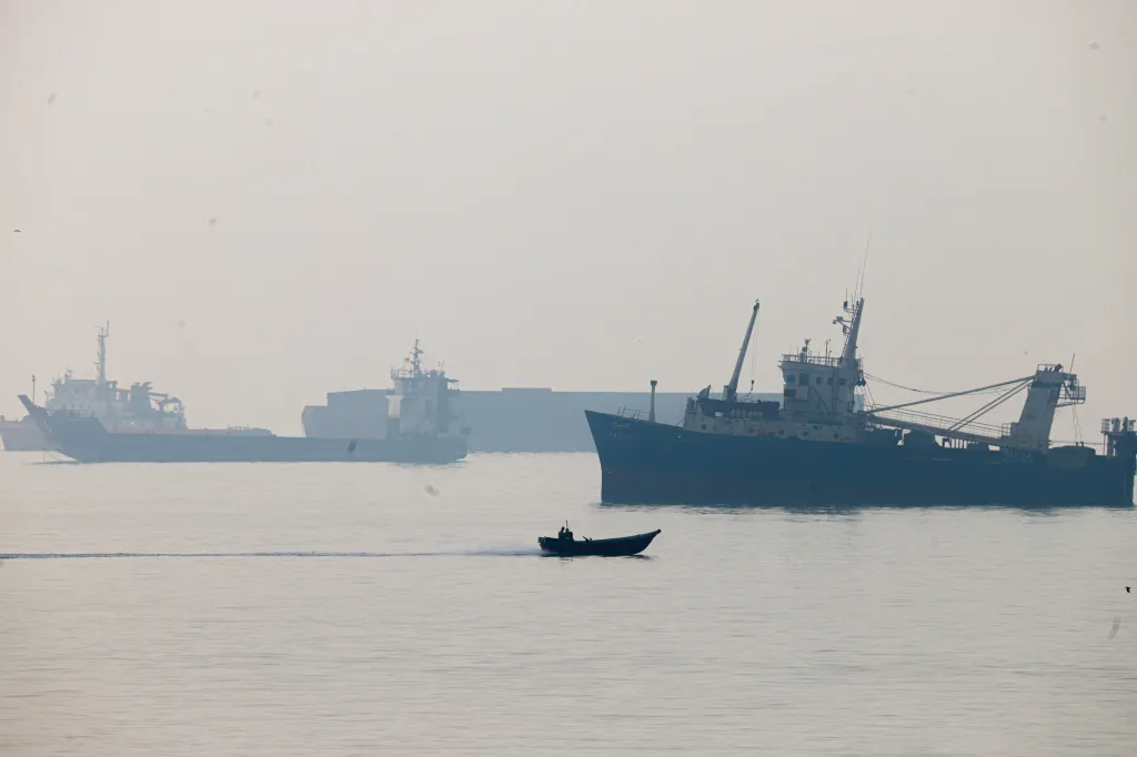 A motorboat travels past commercial vessels anchored in the Strait of Hormuz off Bandar Abbas, Iran.