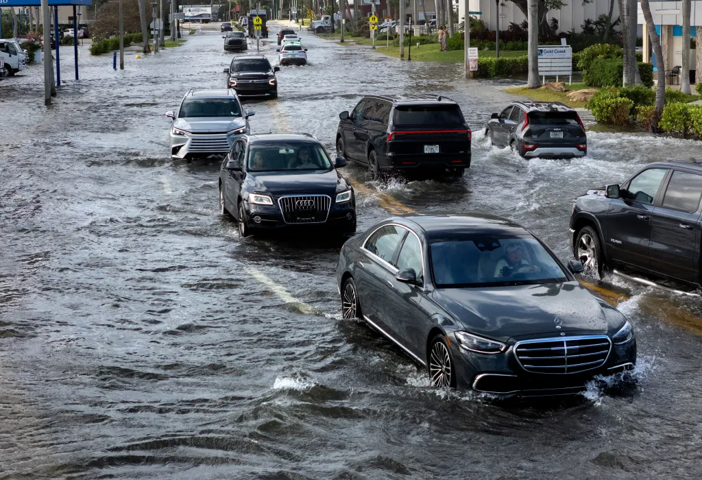 Cars drive through the flooded streets of Flagler Drive.
