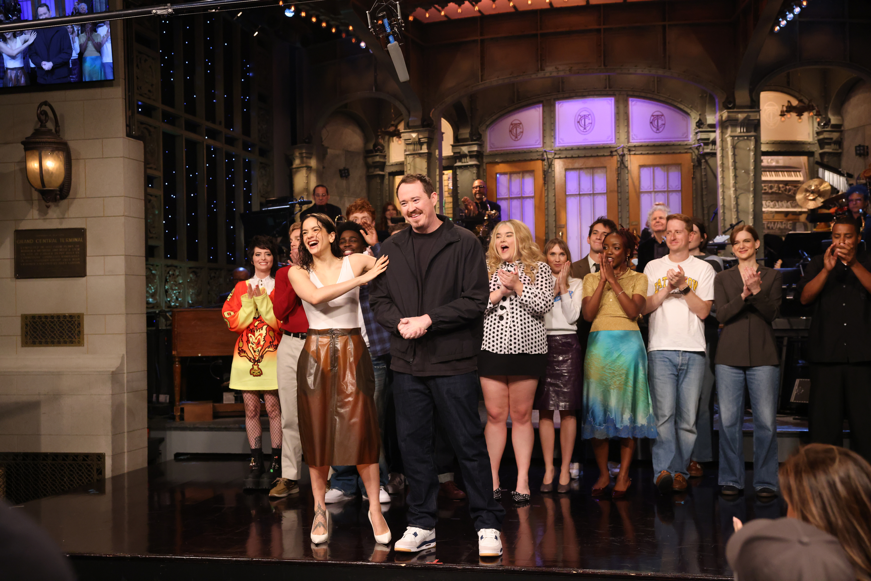 Musical guest Rosalía and host Shane Gillis stand center stage during the Goodnights on Saturday Night Live, surrounded by the cast and band.