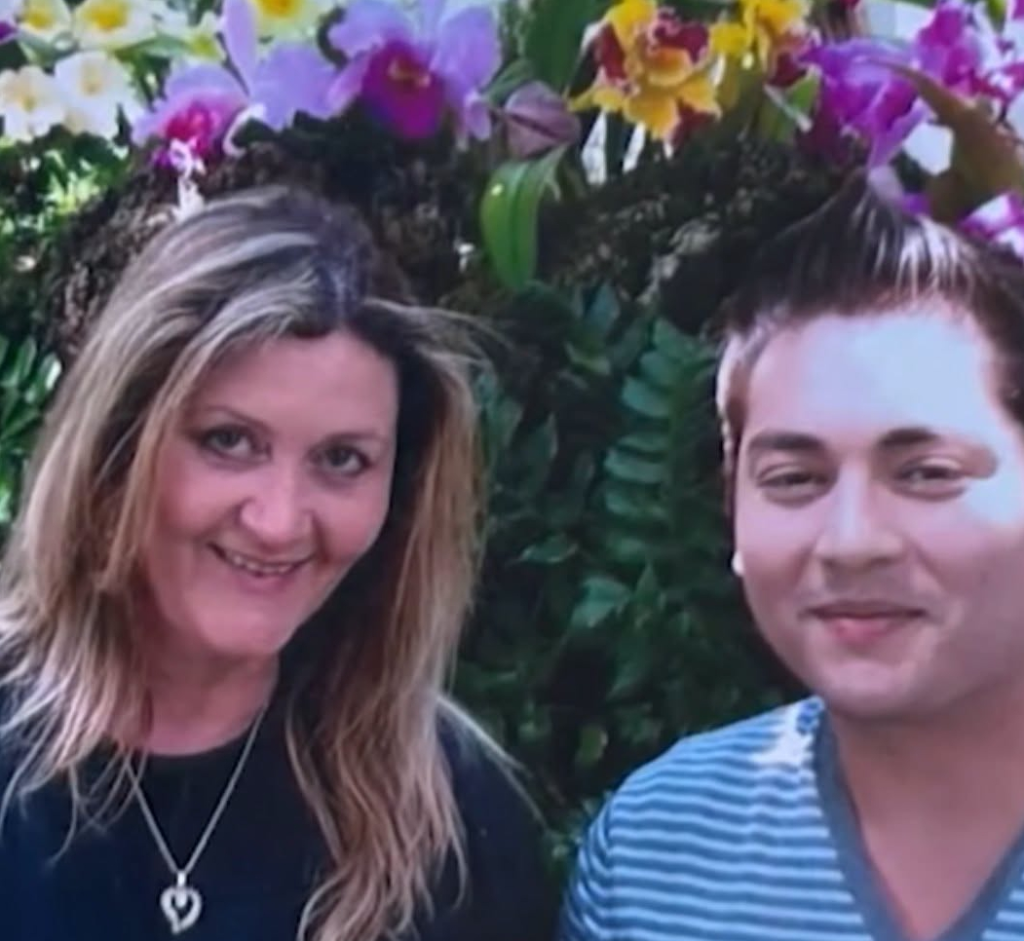 Nadine Jett and her son Cedric von Ferdinand pose together in front of a background of flowering plants.
