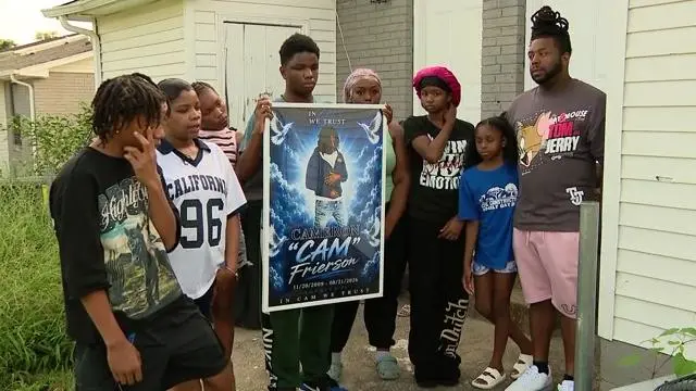 Friends and family of Cameron Frierson hold a memorial poster for the teenager.
