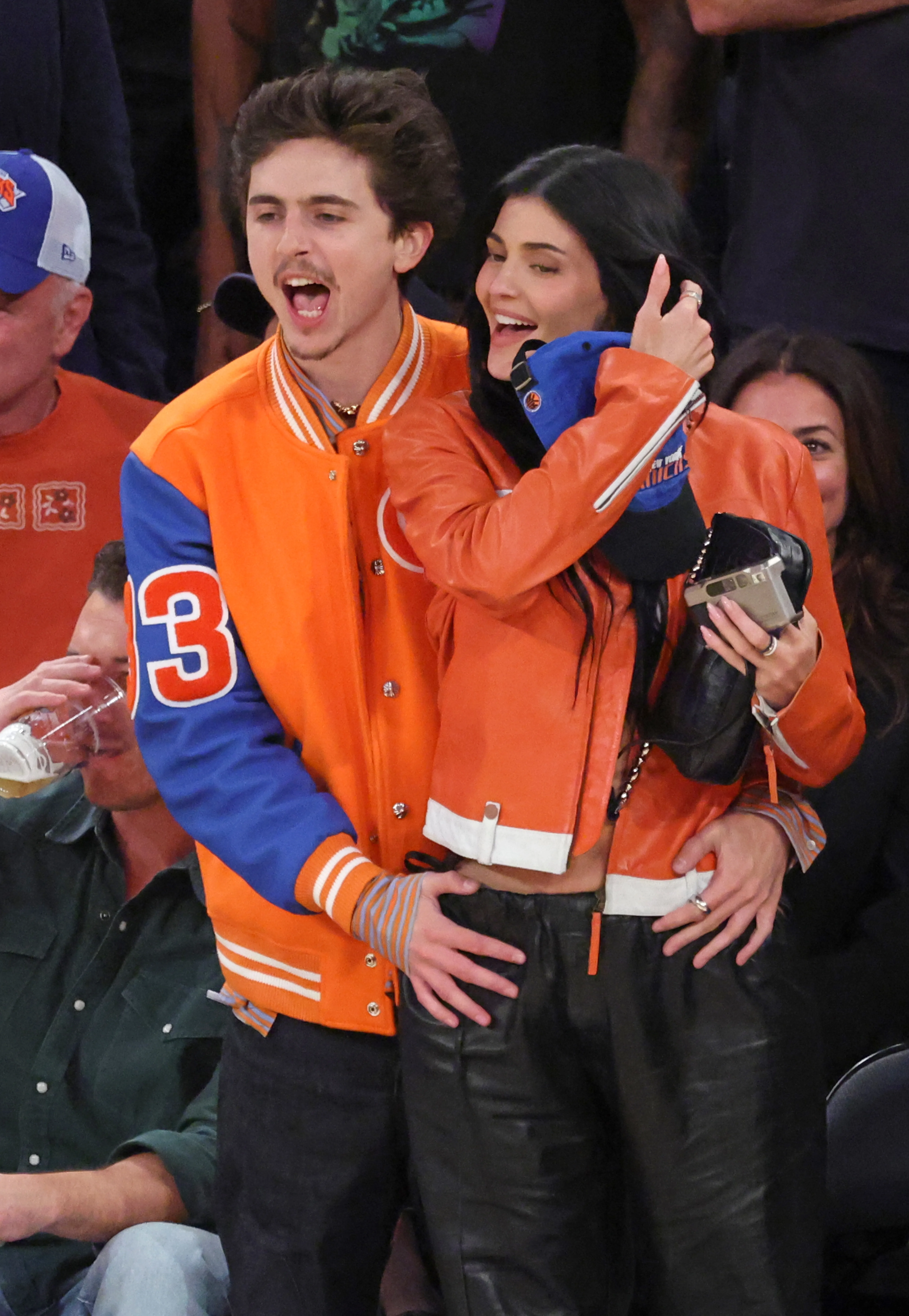Actor Timothée Chalamet and Kylie Jenner stand together smiling at a basketball game.