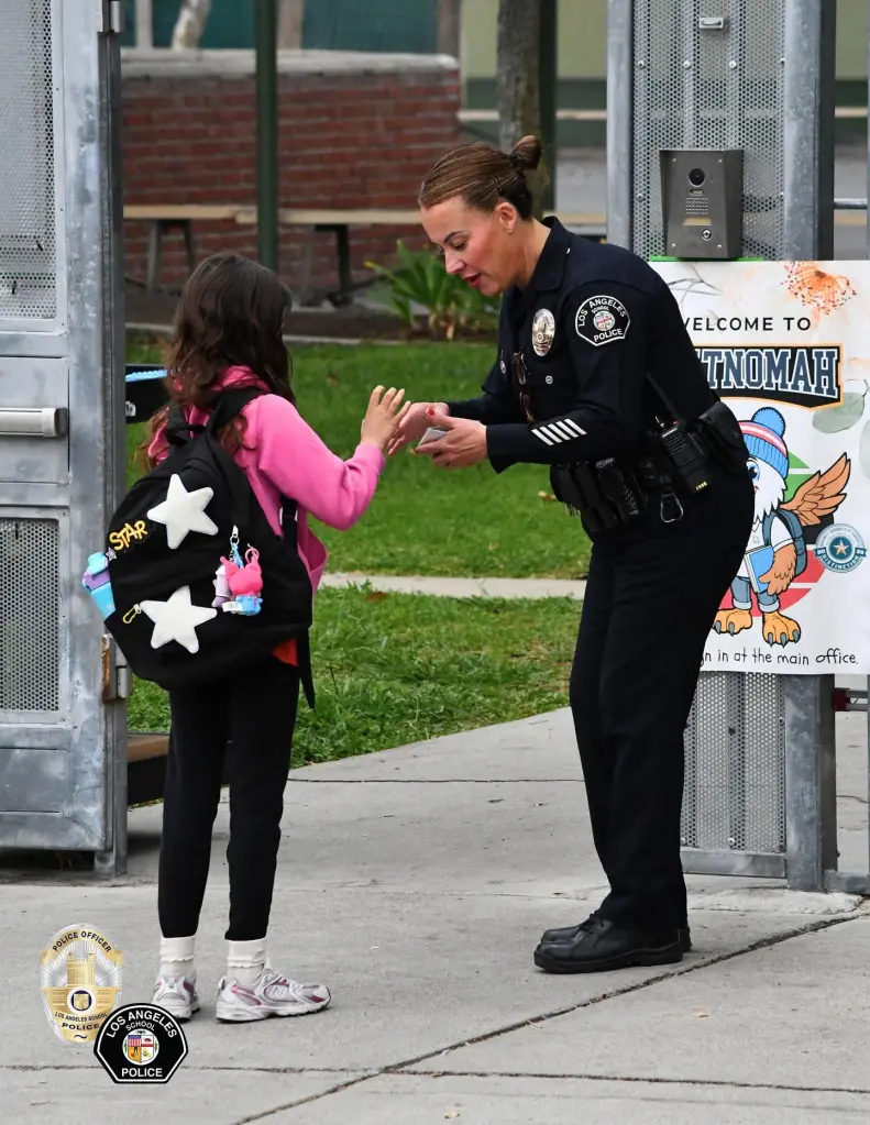 Los Angeles School Police officer greets a student outside a school entrance.