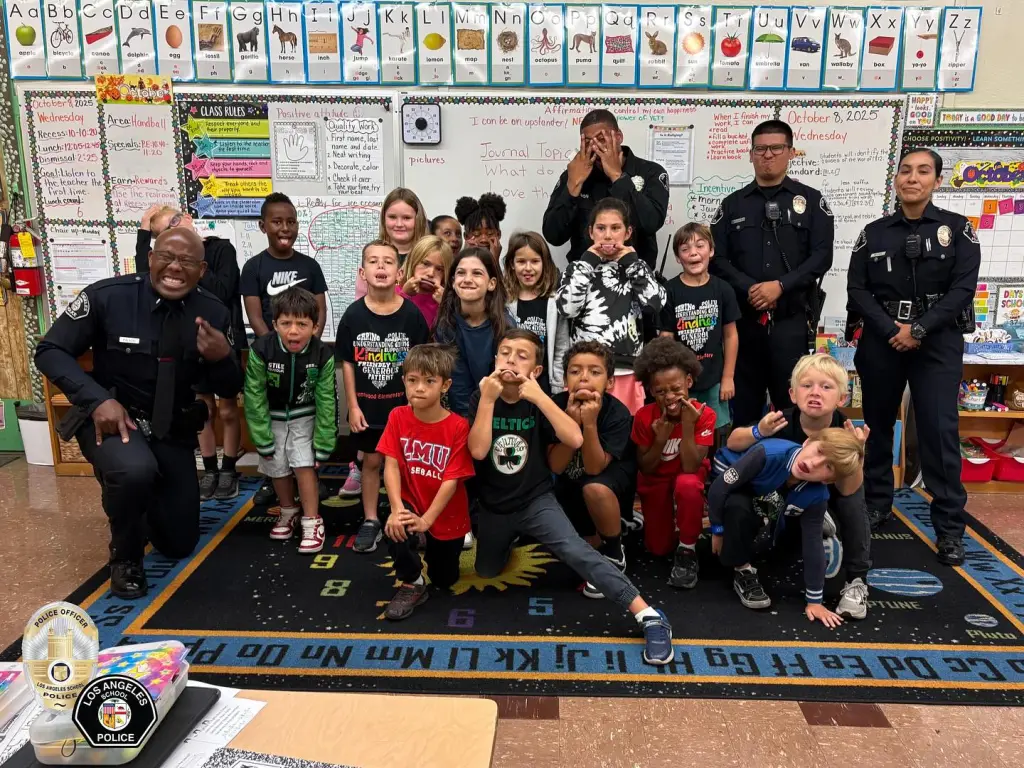 Los Angeles School Police officers pose with a group of elementary school students in a classroom.