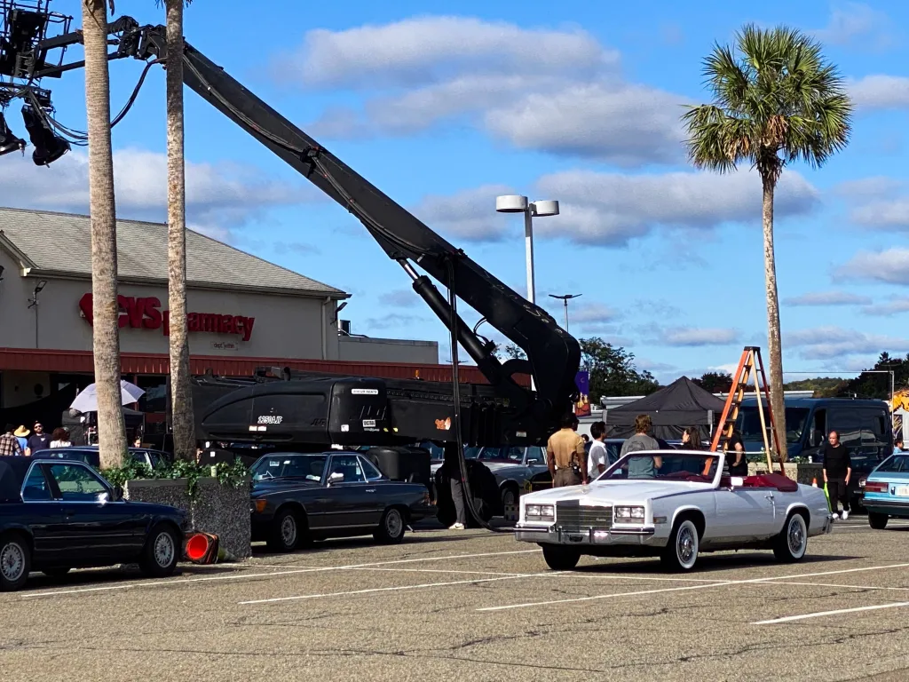 Austin Butler on the set of the film Miami Vice '85 in New Jersey, with a white convertible and film crew equipment.