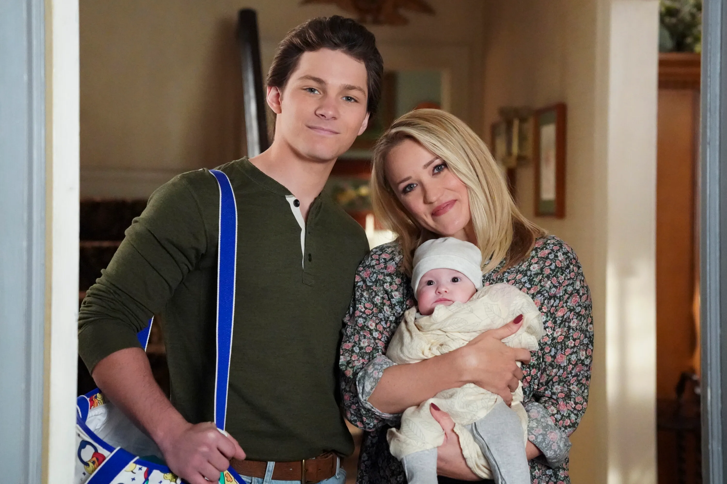 Montana Jordan as Georgie Cooper and Emily Osment as Mandy McAllister holding their baby on Young Sheldon.