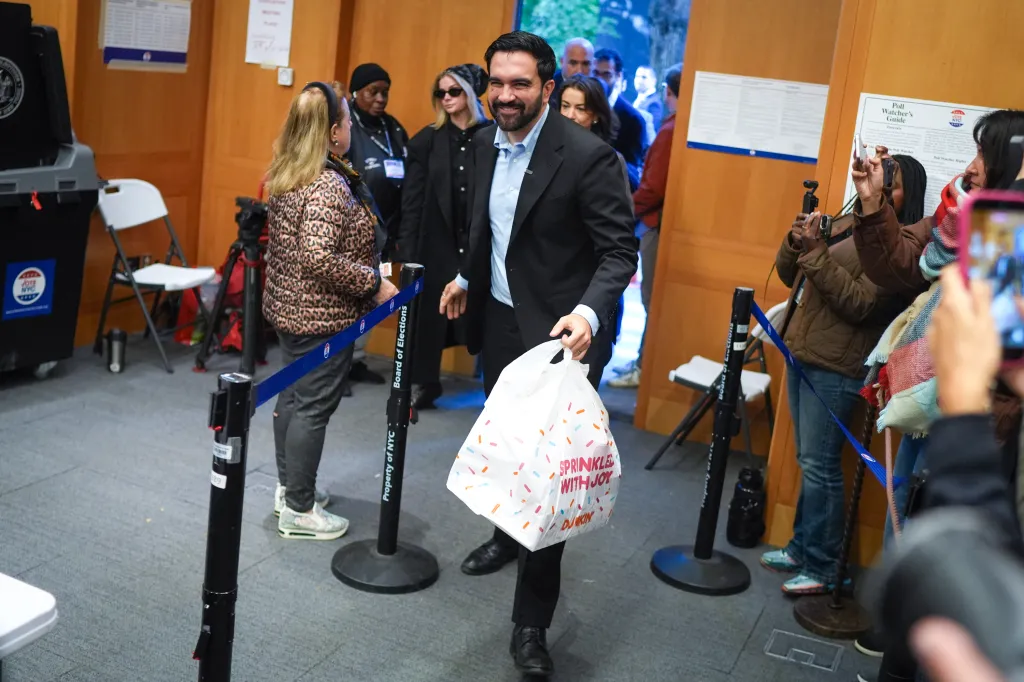 New York City Mayor Zohran Mamdani arrives to a polling site carrying a bag of donuts for poll workers before casting his ballot.