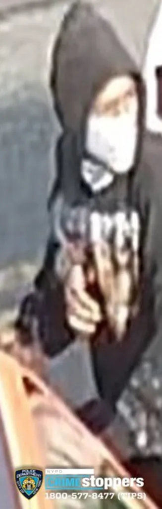 Surveillance image of an individual wearing a dark hooded sweatshirt and a face mask.
