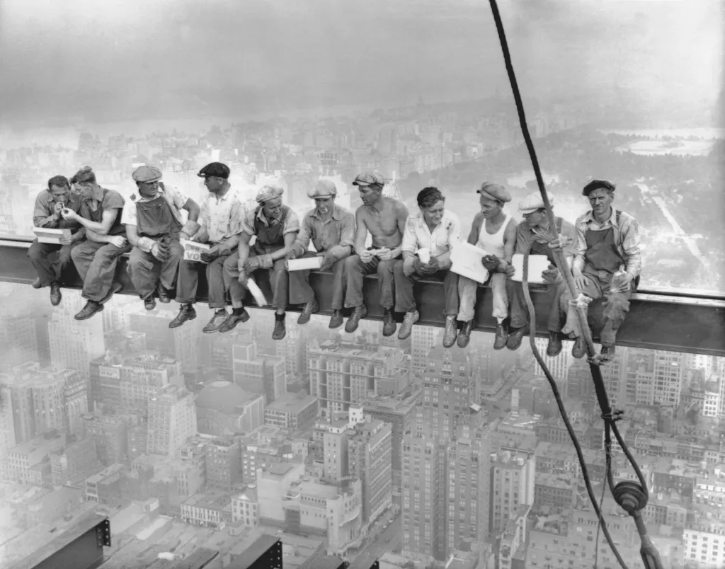 Eleven construction workers sit eating lunch on a steel beam high above New York City.