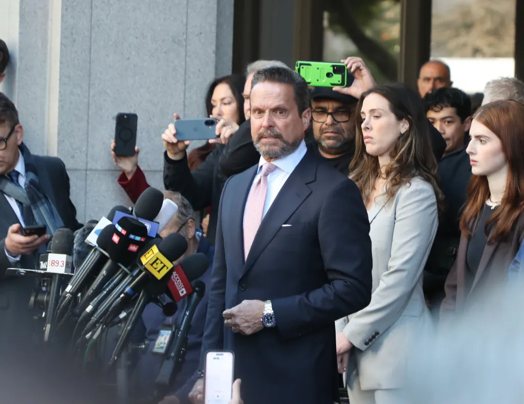 Defense lawyer Alan Jackson speaks to reporters outside a courthouse, surrounded by microphones and cameras.