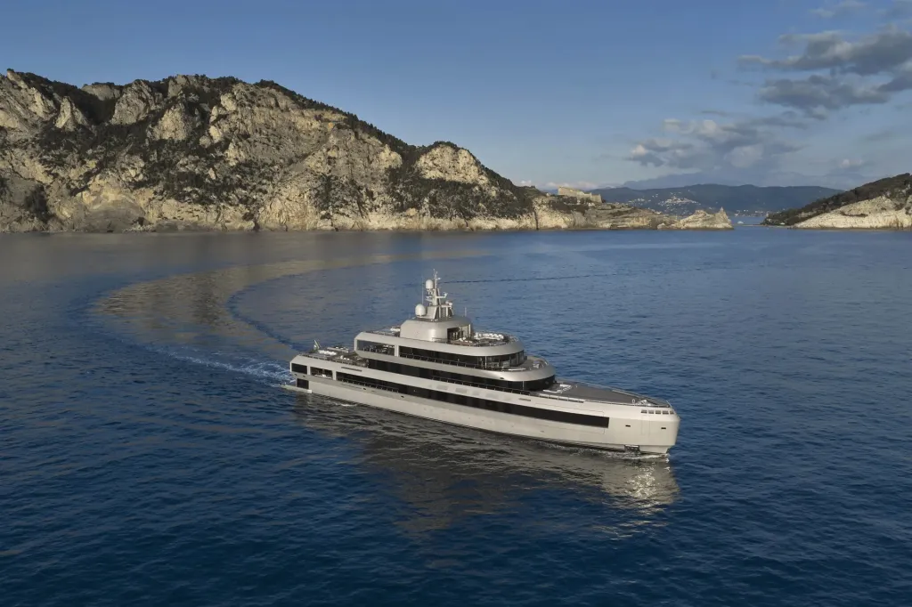 The 72-meter motor yacht No Rush cruising on the sea near a mountainous coastline.