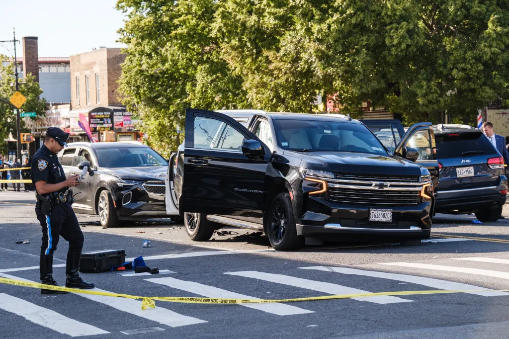NYPD officers investigate the scene of a multiple-vehicle crash involving several cars at an intersection.