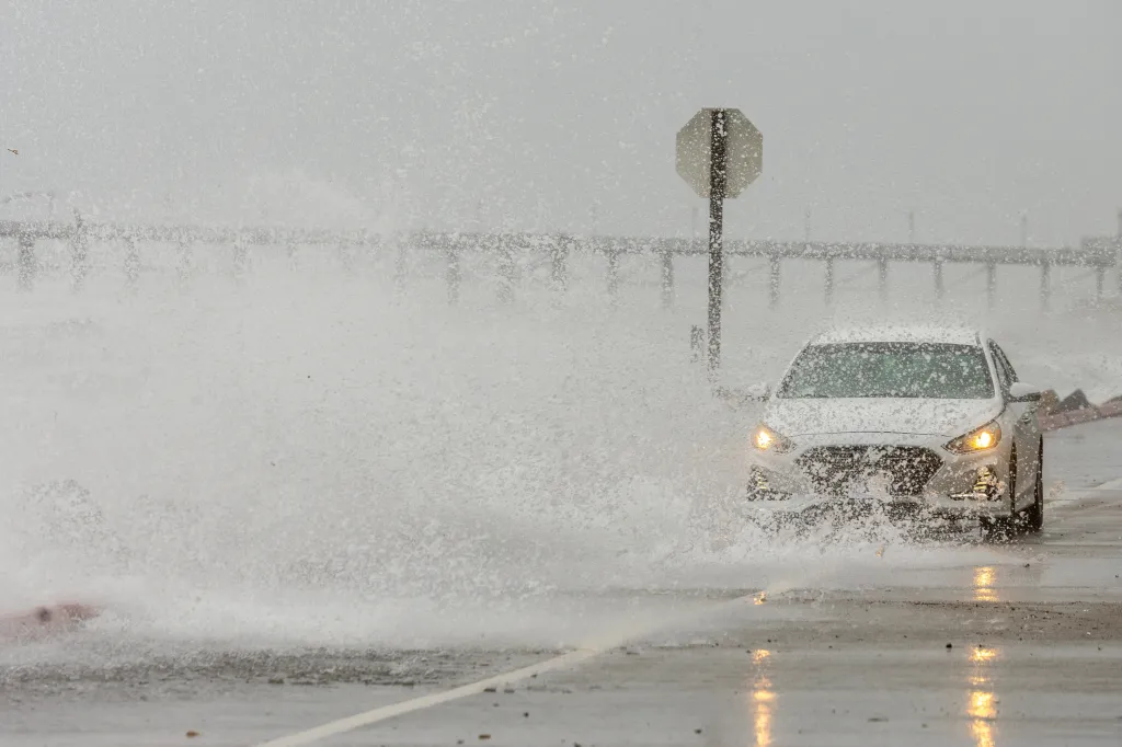 Ocean waves from post-tropical cyclone Rachel impact the coastline, crashing over a road and splashing a car in Oceanside, California.