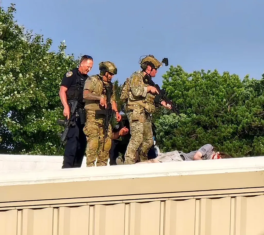 Law enforcement officers stand on a roof near the body of shooter Thomas Matthew Crooks.