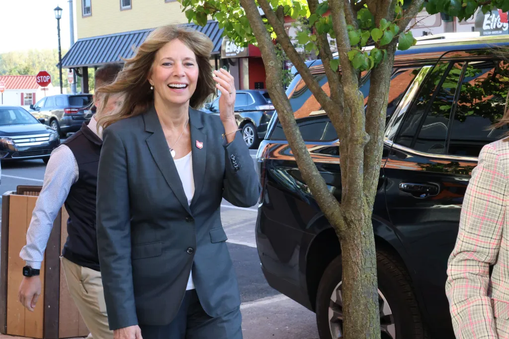 Ohio Democratic gubernatorial candidate Dr. Amy Acton smiles and adjusts her hair while walking outdoors.