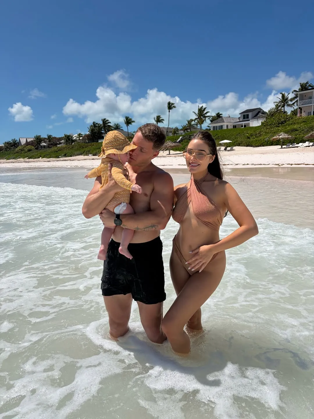 Olivia Culpo and Christian McCaffrey with their baby in the ocean.