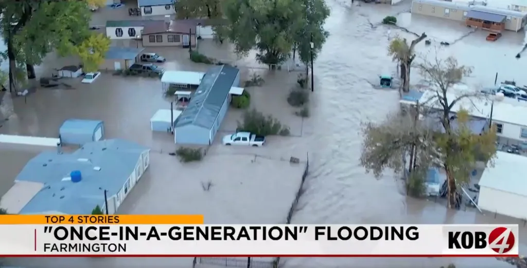 Aerial view of severe flooding surrounding homes and vehicles in a residential area.