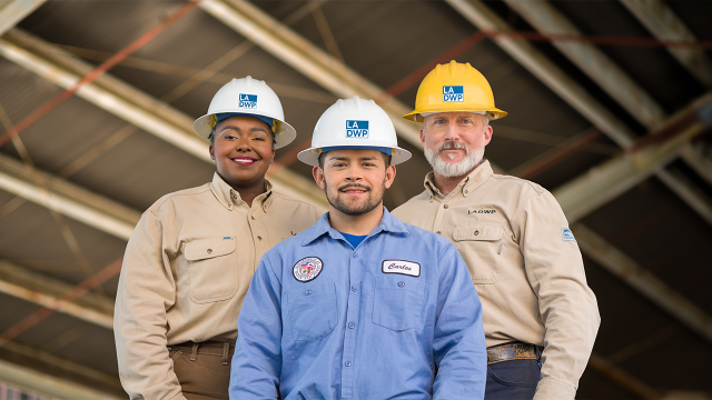 Three LADWP employees wearing hard hats posing together.