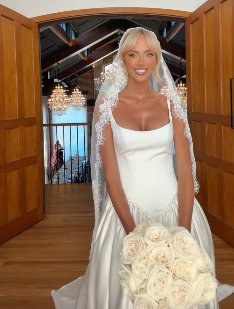OnlyFans star Annie Knight in a wedding dress and veil holding a bouquet of white roses during her wedding ceremony.