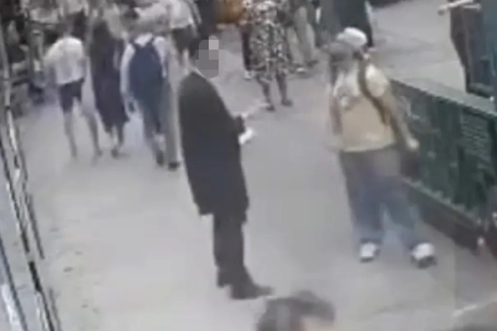 Surveillance footage shows an Orthodox Jewish man and another person on a crowded sidewalk in Midtown Manhattan.