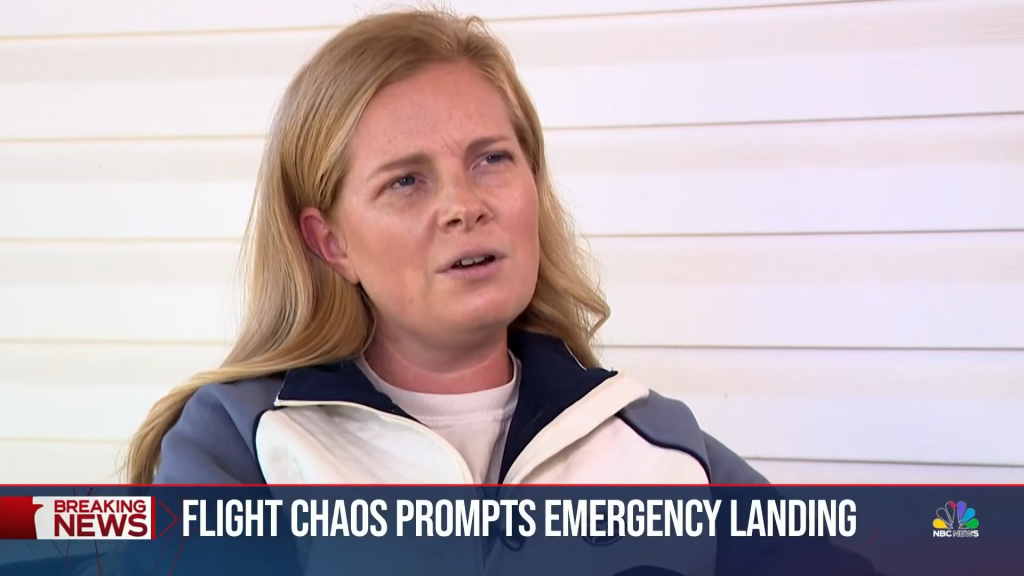 A blonde woman in a white and blue jacket is interviewed on a news broadcast with a banner reading 