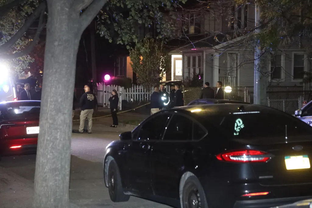 Police investigate a shooting scene at night on a residential street in Queens, New York.