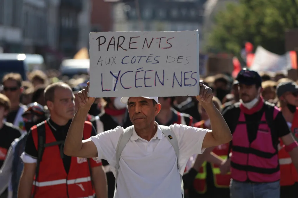 A parent holds a placard reading 