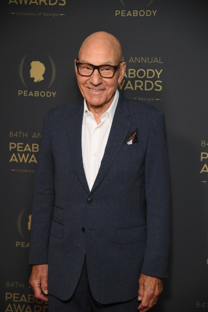 Patrick Stewart smiling in a dark blue suit and white shirt at the Peabody Awards.