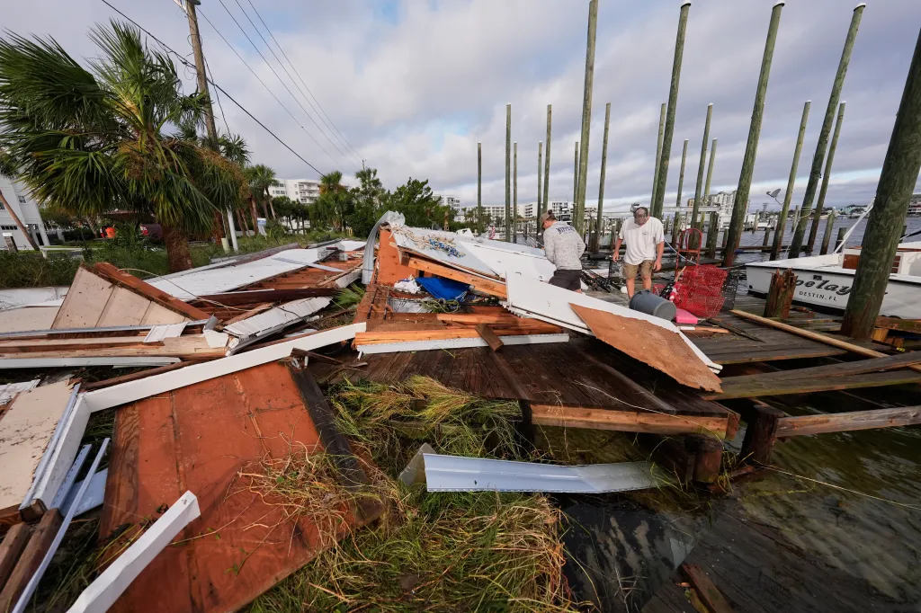 People retrieve belongings from a collapsed boat house in the aftermath of a hurricane.