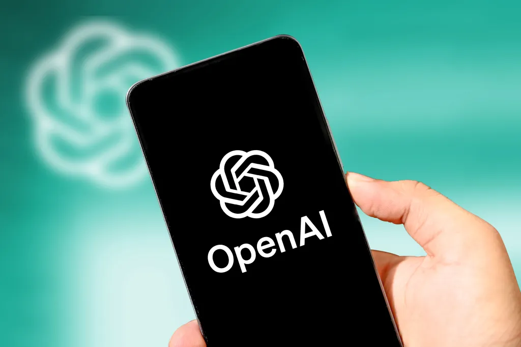A person holding a smartphone displaying the OpenAI logo on screen against a green background.