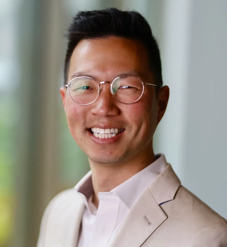 Phil Kim smiling and wearing round glasses.
