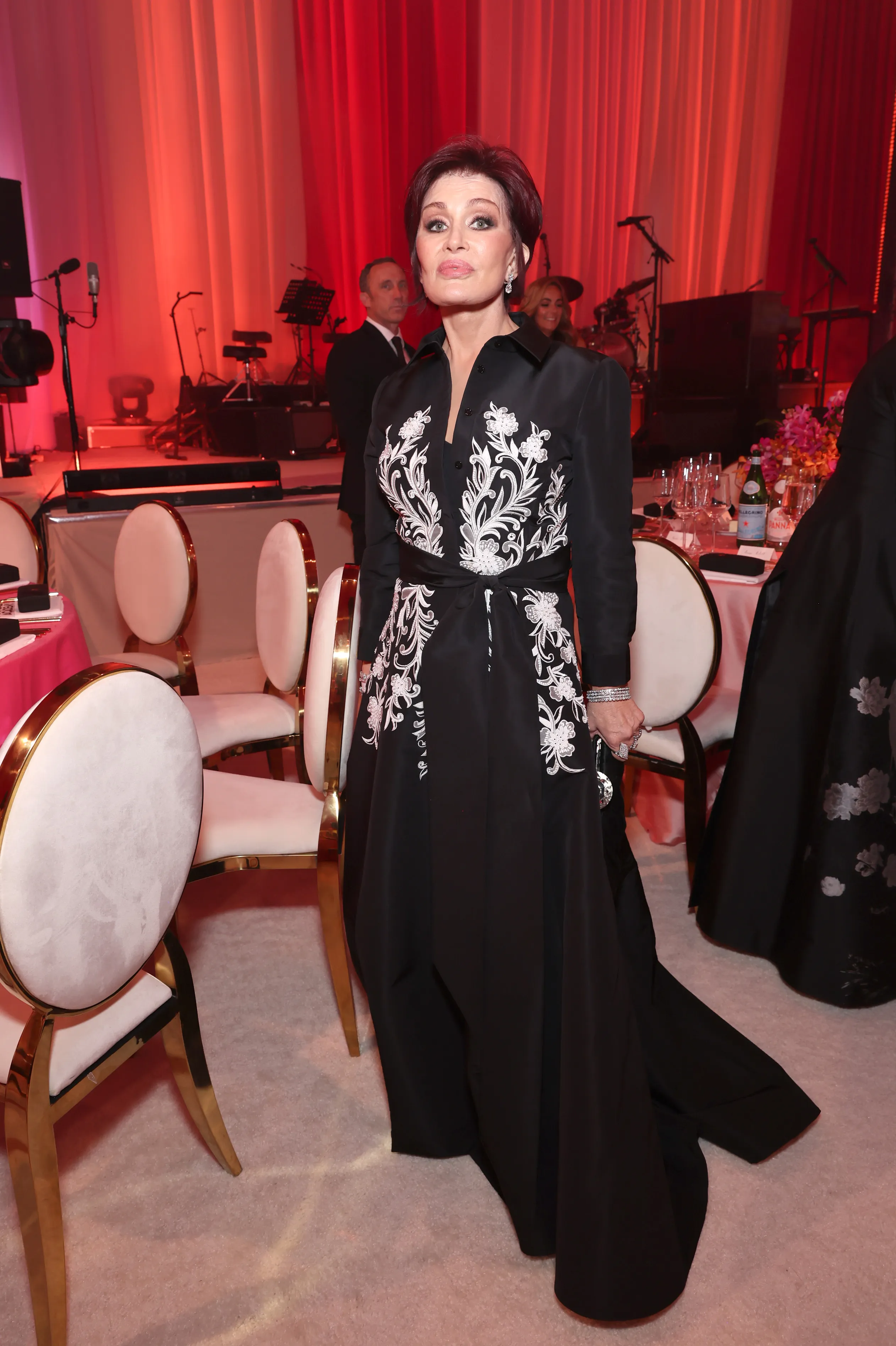 Sharon Osbourne wears a black long-sleeved dress with white floral embroidery at an Oscars viewing party.